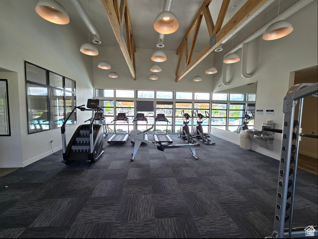 Gym featuring a towering ceiling and dark carpet