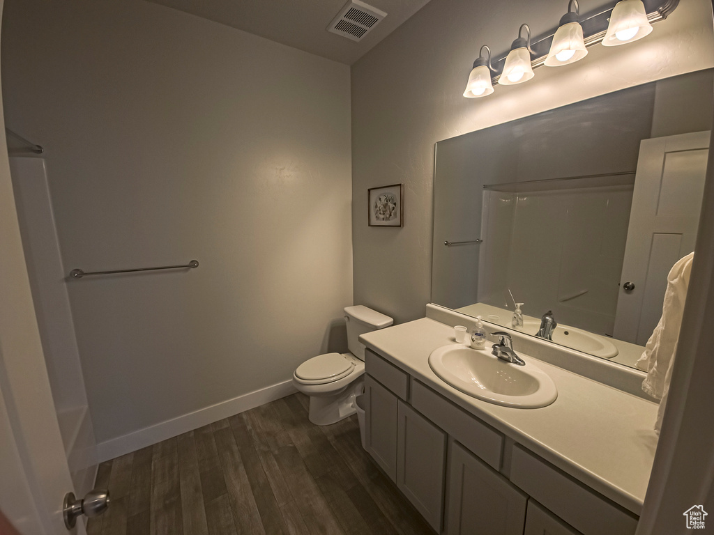 Bathroom with large vanity, toilet, and wood-type flooring