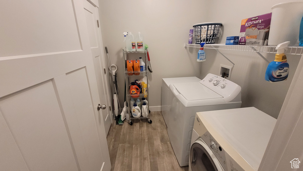 Washroom with hookup for a washing machine, washing machine and clothes dryer, and light wood-type flooring