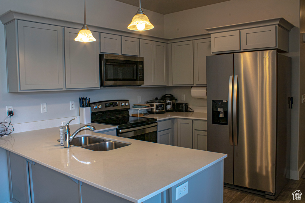 Kitchen with gray cabinets, dark wood-type flooring, appliances with stainless steel finishes, sink, and pendant lighting