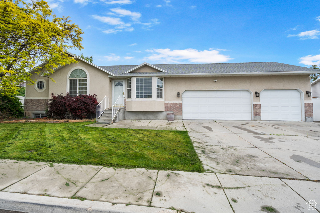 Single story home with a garage and a front lawn