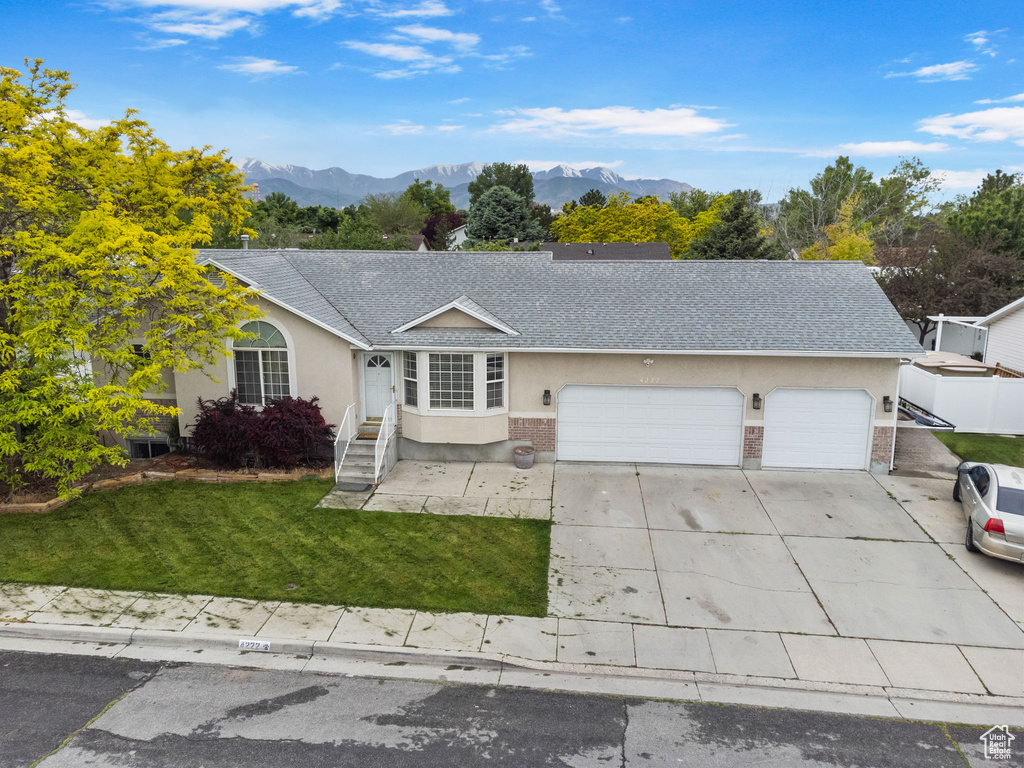 Single story home with a garage, a mountain view, and a front lawn