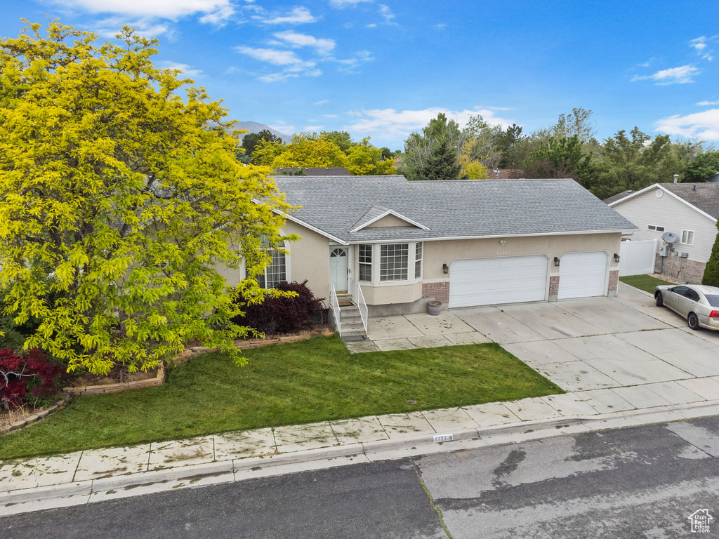 Single story home with a garage and a front lawn