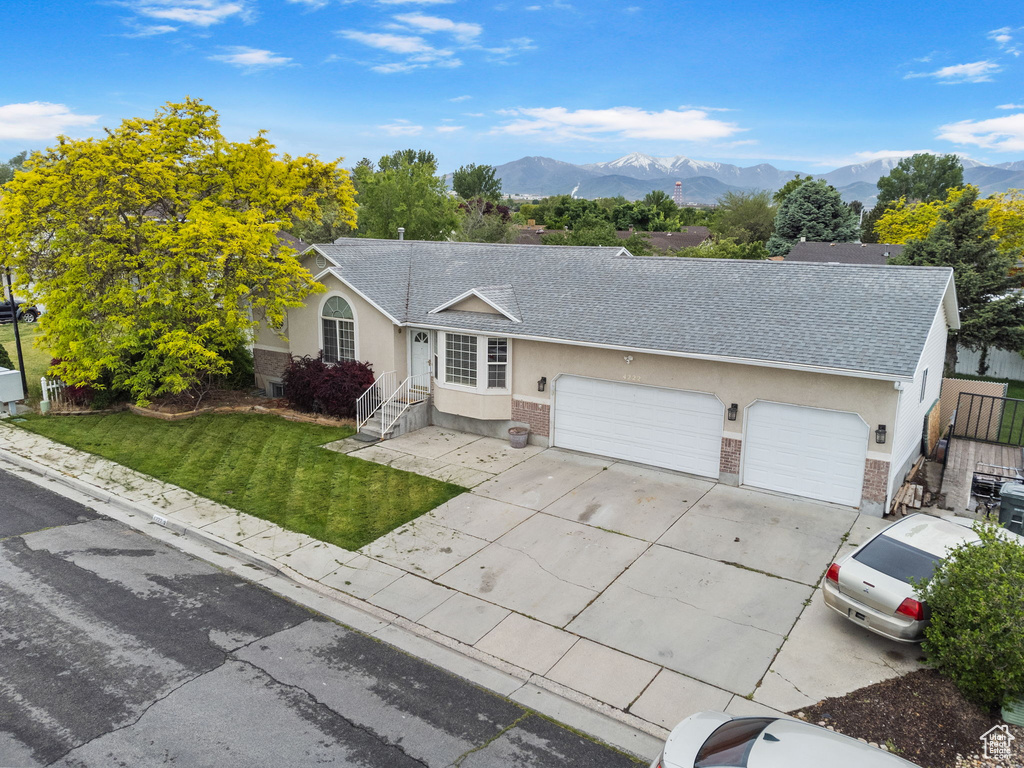 Single story home with a front yard, a garage, and a mountain view