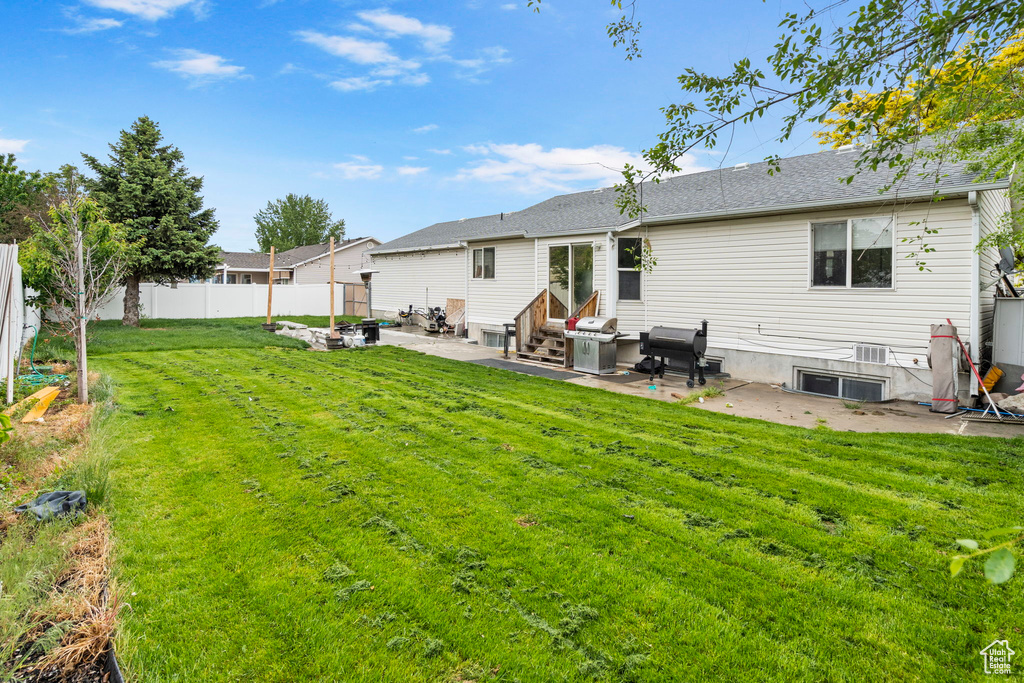 Rear view of property featuring a yard and a patio area