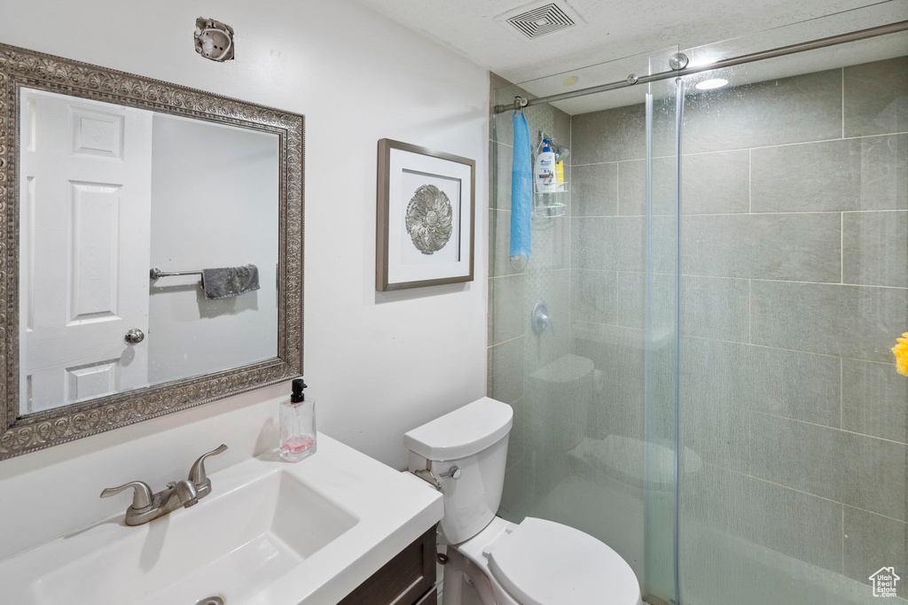 Bathroom with vanity, toilet, and a shower with door