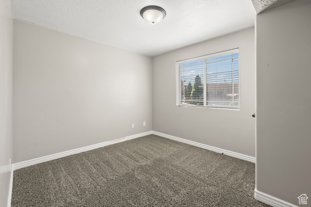 Spare room featuring dark carpet