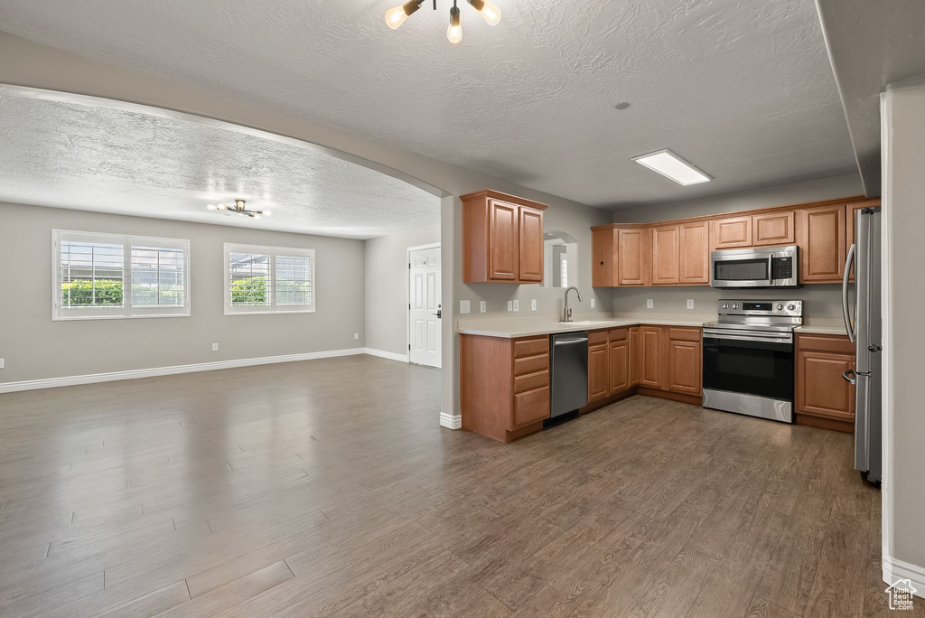 Kitchen with appliances with stainless steel finishes, sink, a textured ceiling, and dark hardwood / wood-style floors