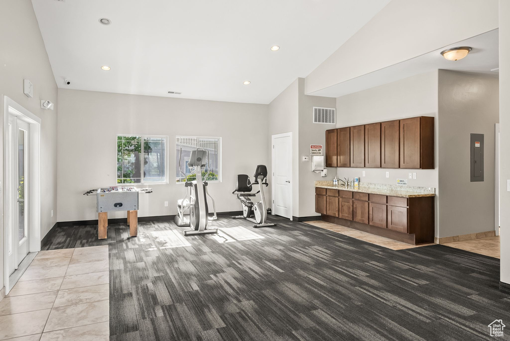 Workout area featuring high vaulted ceiling, sink, and tile floors