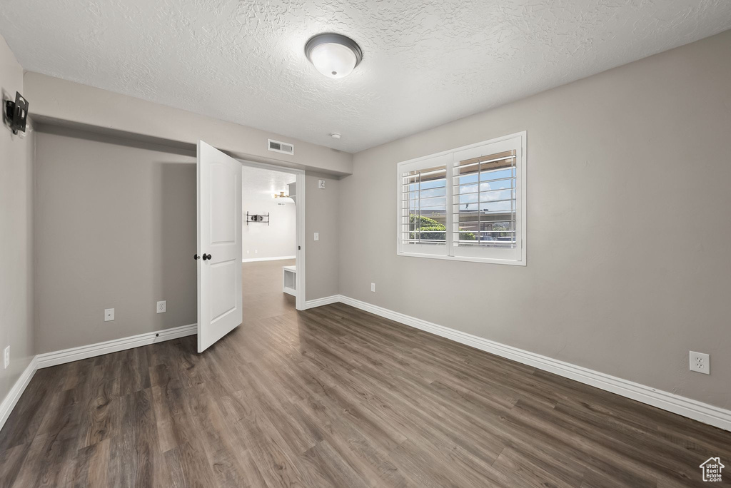 Unfurnished bedroom with a textured ceiling and dark hardwood / wood-style floors