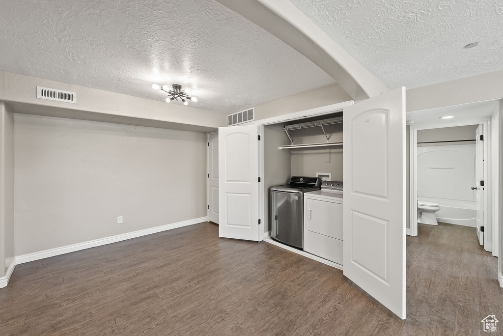 Interior space featuring separate washer and dryer, a textured ceiling, and dark hardwood / wood-style floors