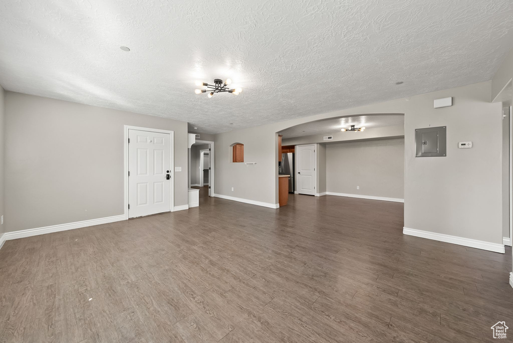 Empty room with a textured ceiling and dark hardwood / wood-style flooring