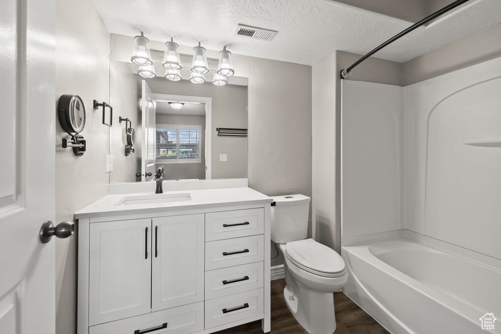 Full bathroom with toilet, hardwood / wood-style floors,  shower combination, vanity, and a textured ceiling