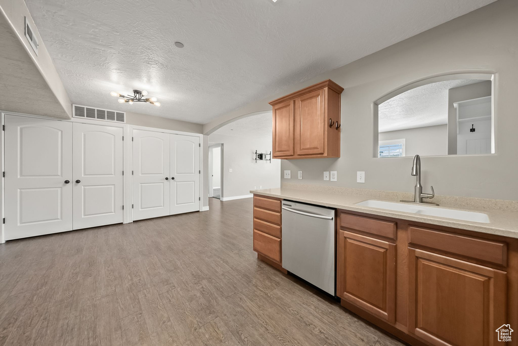 Kitchen with sink, hardwood / wood-style flooring, a textured ceiling, and stainless steel dishwasher