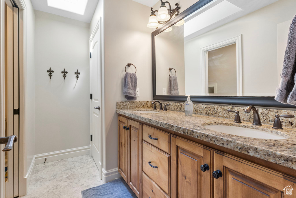 Bathroom featuring tile flooring, double sink, a skylight, and vanity with extensive cabinet space