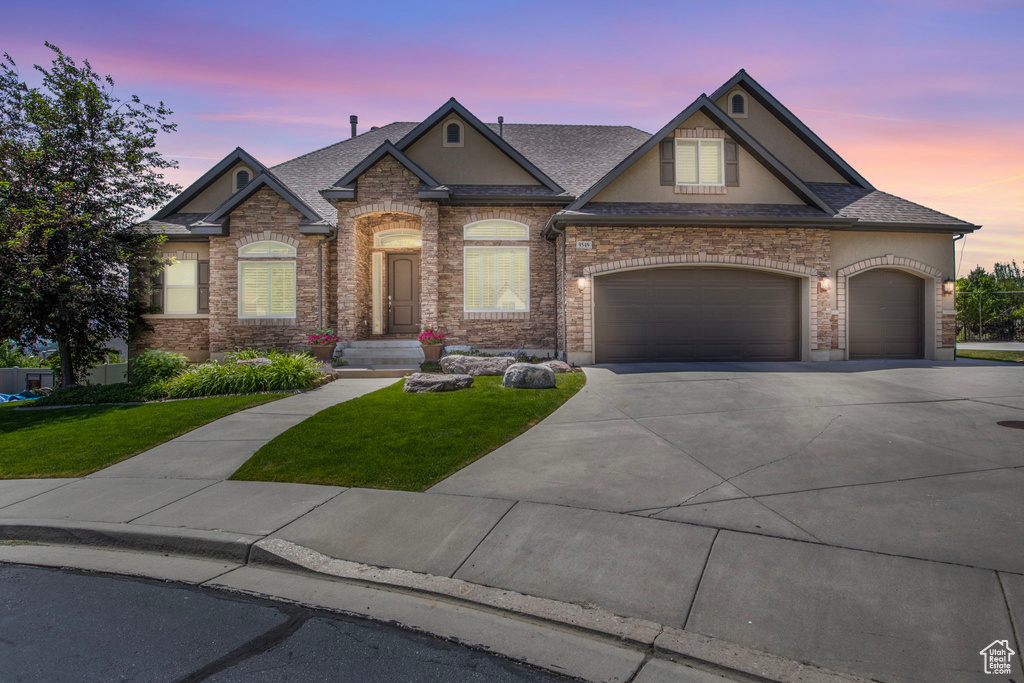 View of front of home with a garage and a lawn