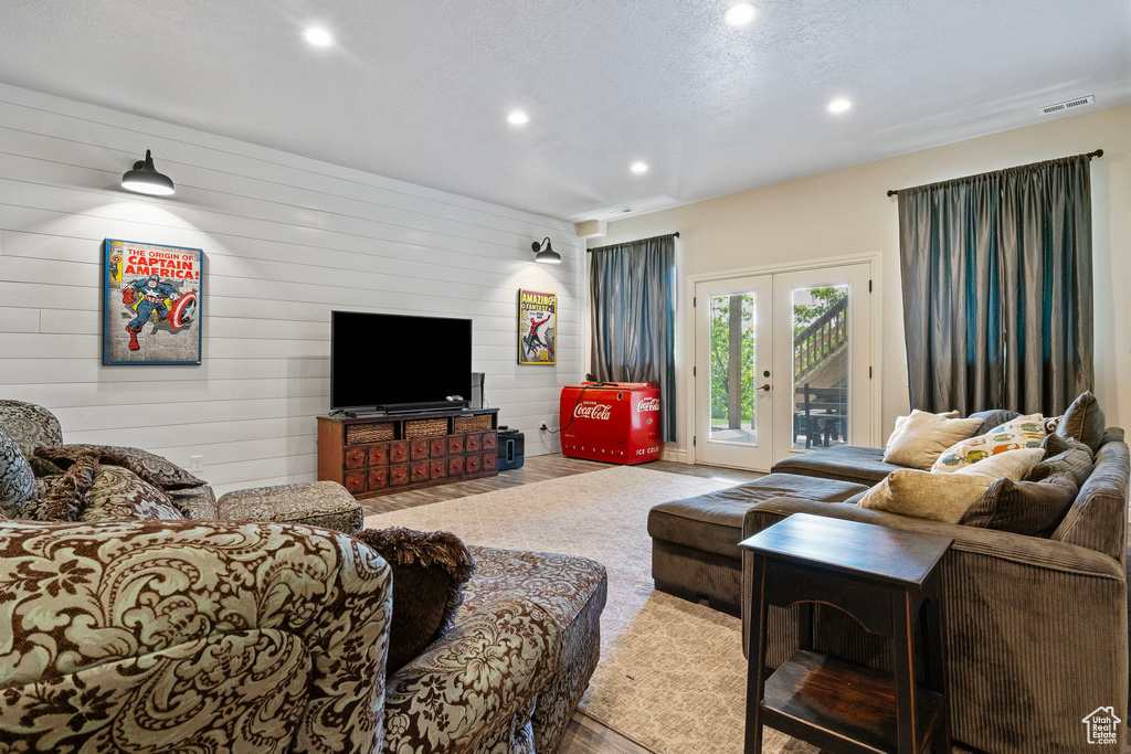 Living room featuring french doors, wood walls, and a textured ceiling