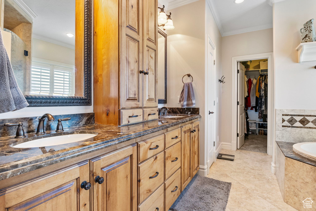 Bathroom featuring tile floors, ornamental molding, a relaxing tiled bath, and double sink vanity