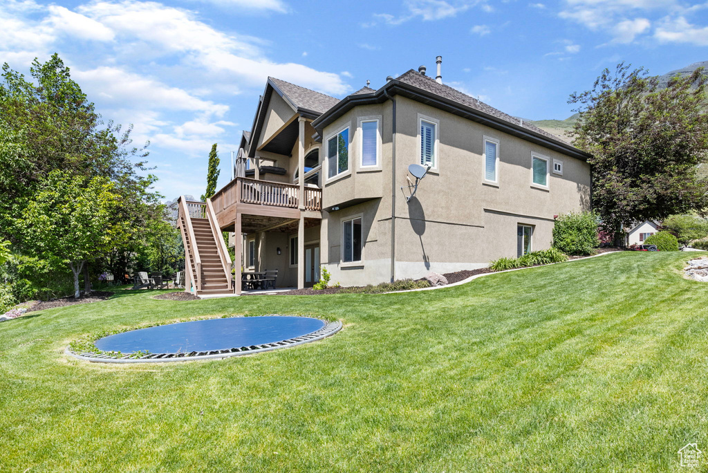 Rear view of property featuring a wooden deck and a yard