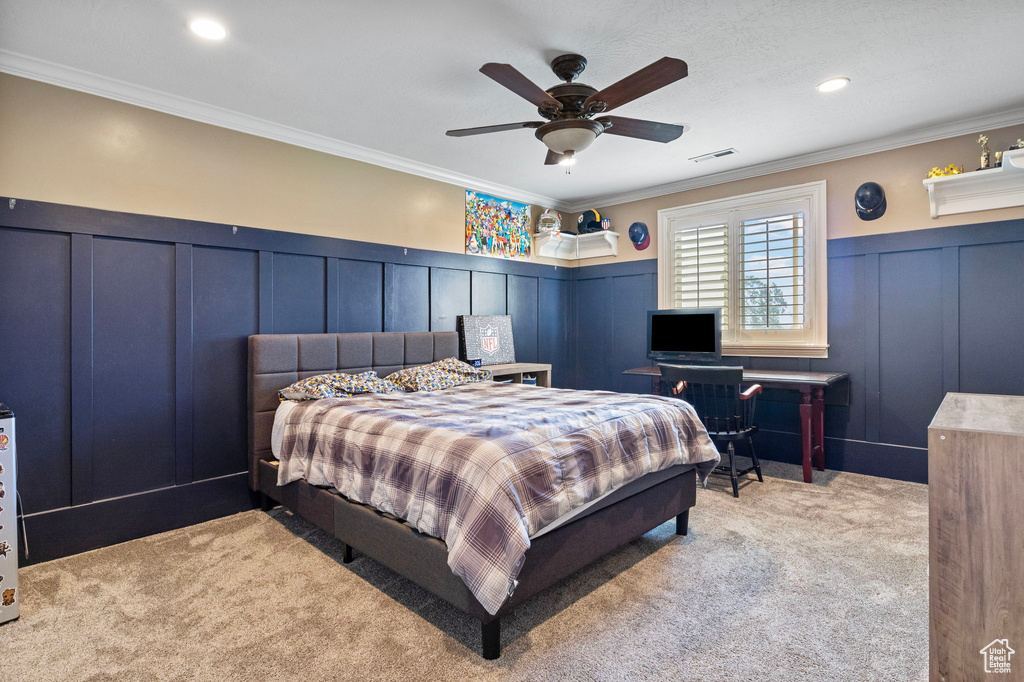 Bedroom with ceiling fan, light colored carpet, and ornamental molding