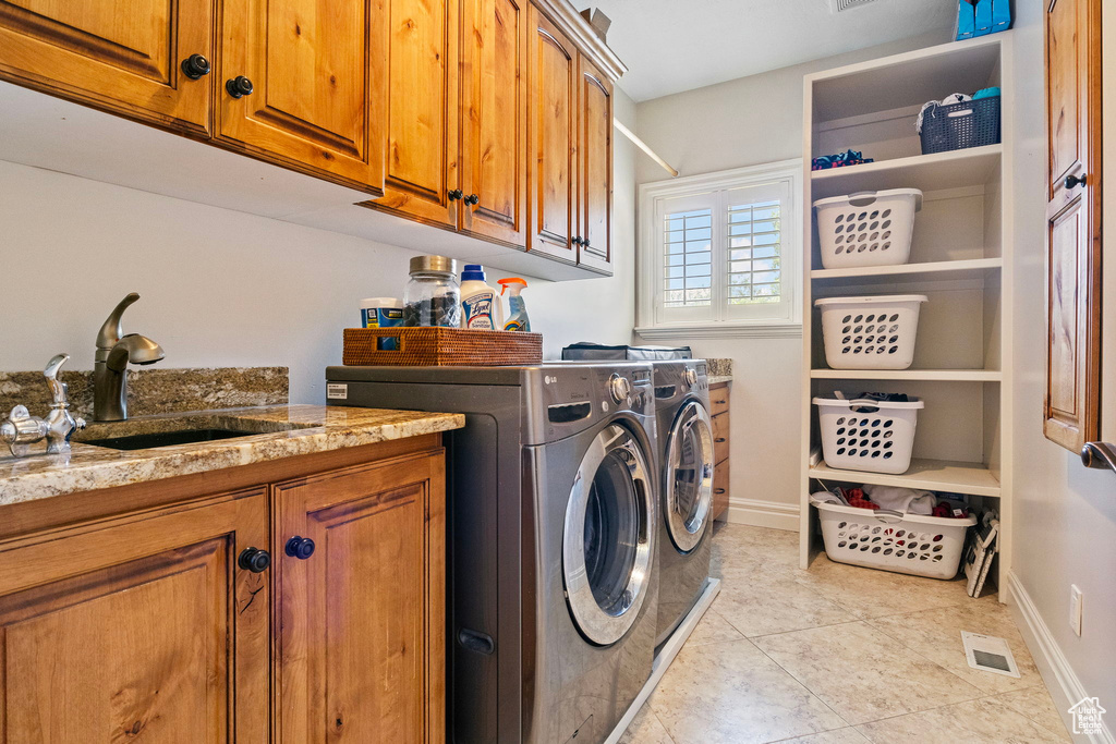 Washroom with separate washer and dryer, sink, cabinets, and light tile floors