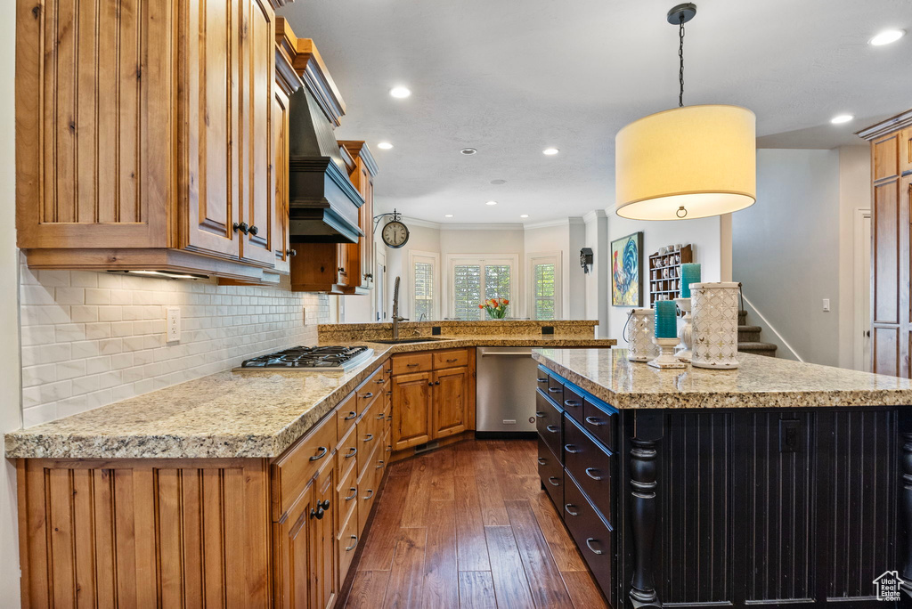 Kitchen with crown molding, stainless steel appliances, dark hardwood / wood-style flooring, a kitchen island, and backsplash