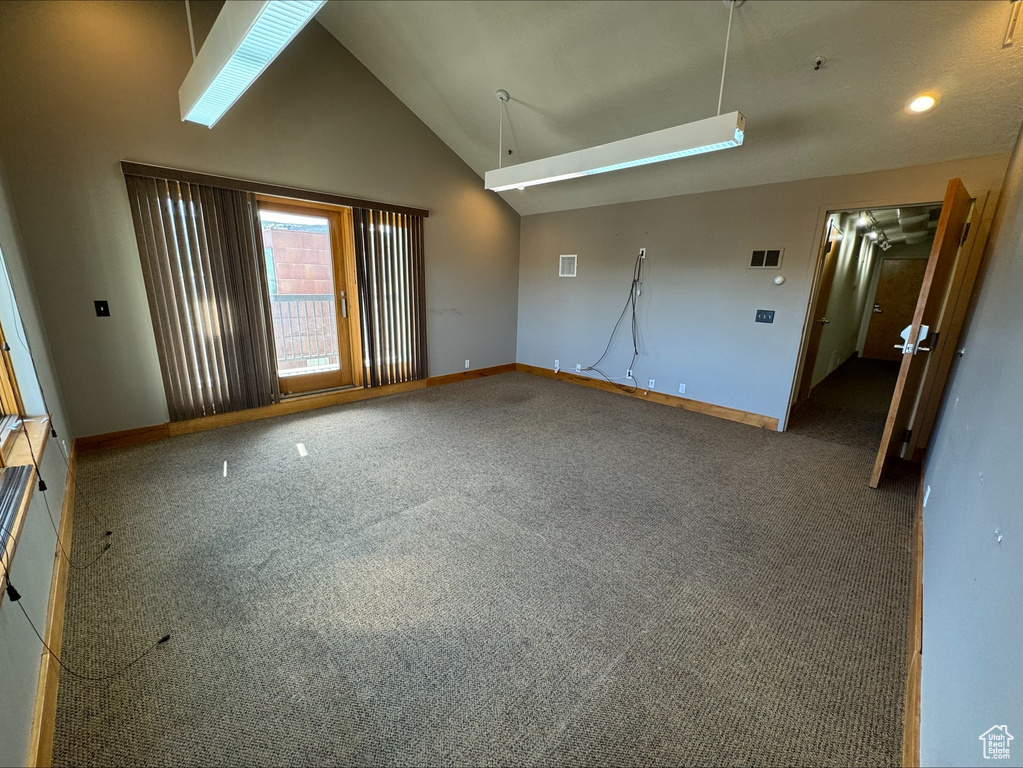 Carpeted empty room featuring high vaulted ceiling