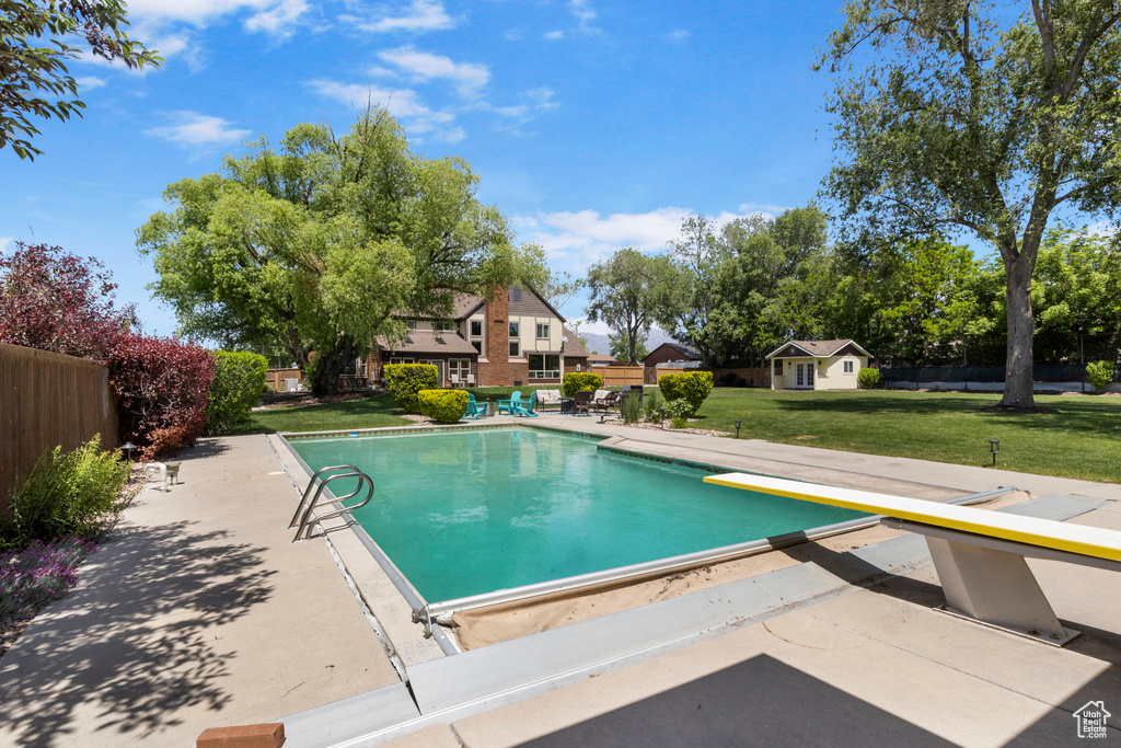 View of swimming pool with a patio area, a diving board, and a yard