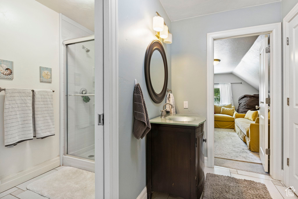 Bathroom featuring vaulted ceiling, an enclosed shower, vanity, and tile floors