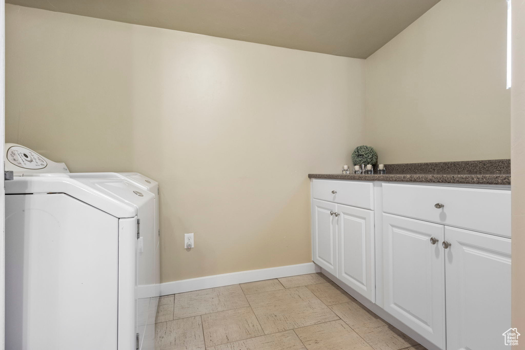 Washroom featuring cabinets, light tile floors, and washing machine and dryer