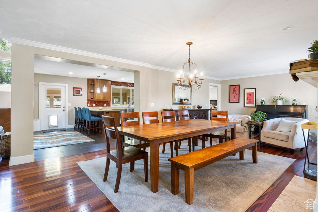 Dining room with an inviting chandelier, crown molding, and hardwood / wood-style flooring