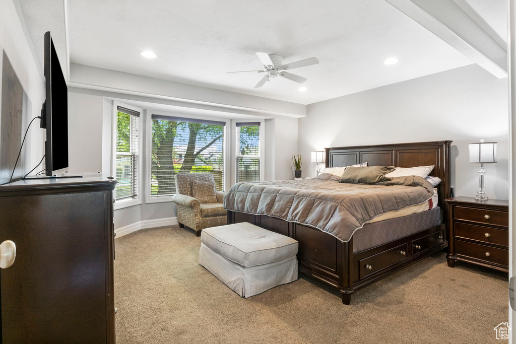 Carpeted bedroom featuring beam ceiling and ceiling fan