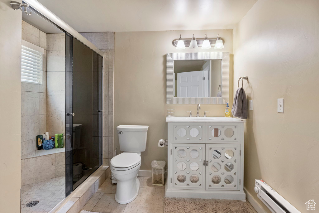 Bathroom featuring walk in shower, a baseboard radiator, large vanity, and toilet