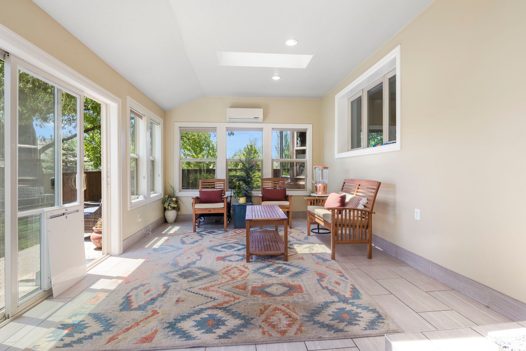 Sunroom / solarium with a wall mounted AC, a wealth of natural light, and lofted ceiling with skylight