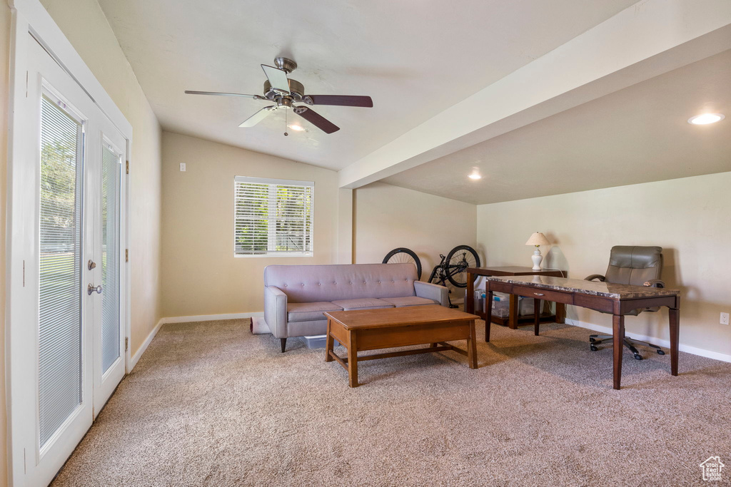 Carpeted living room featuring ceiling fan and lofted ceiling with beams