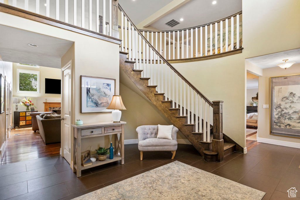 Stairs with dark hardwood / wood-style flooring and a high ceiling