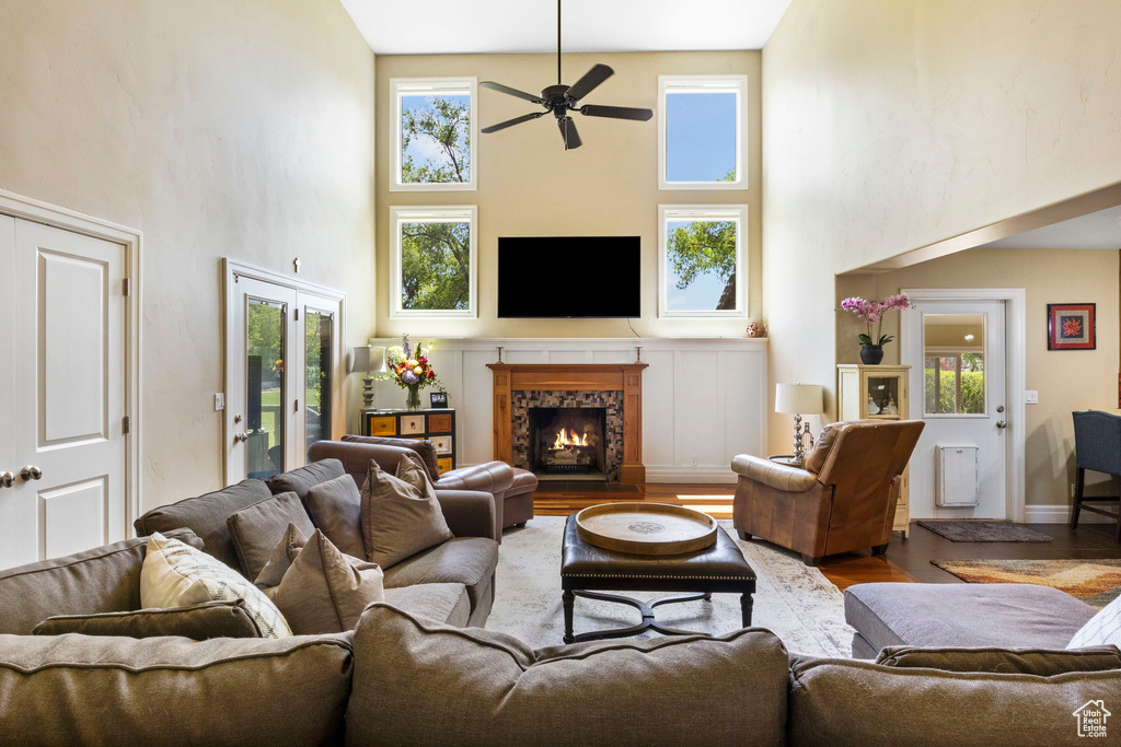 Living room with a high ceiling, wood-type flooring, and ceiling fan