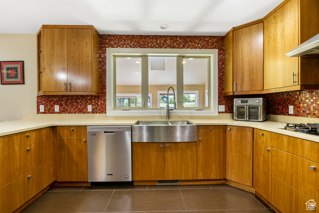 Kitchen featuring dark tile floors, stainless steel appliances, backsplash, and sink