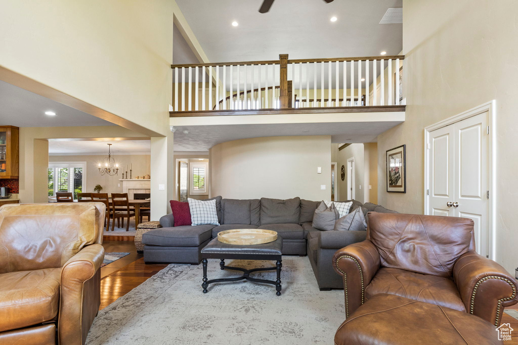 Living room with hardwood / wood-style floors, a high ceiling, and ceiling fan with notable chandelier