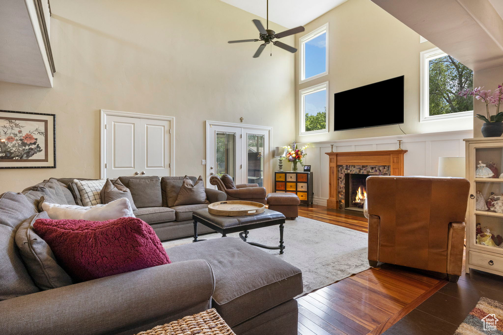 Living room featuring french doors, dark wood-type flooring, a tile fireplace, a high ceiling, and ceiling fan