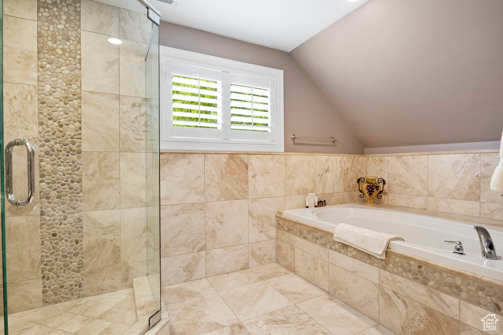 Bathroom featuring tile flooring, tile walls, lofted ceiling, and independent shower and bath