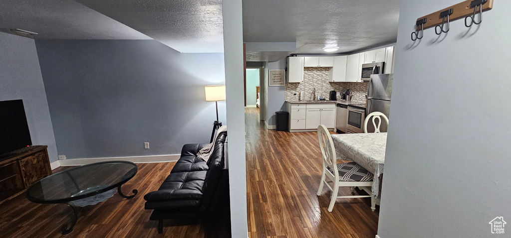 Kitchen featuring backsplash, appliances with stainless steel finishes, white cabinetry, and dark hardwood / wood-style floors