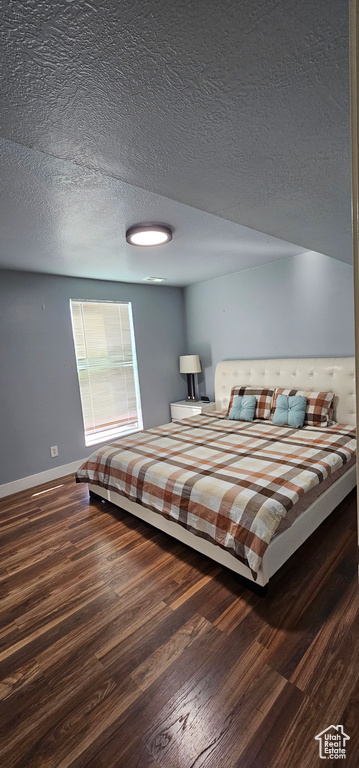 Bedroom featuring dark wood-type flooring and a textured ceiling