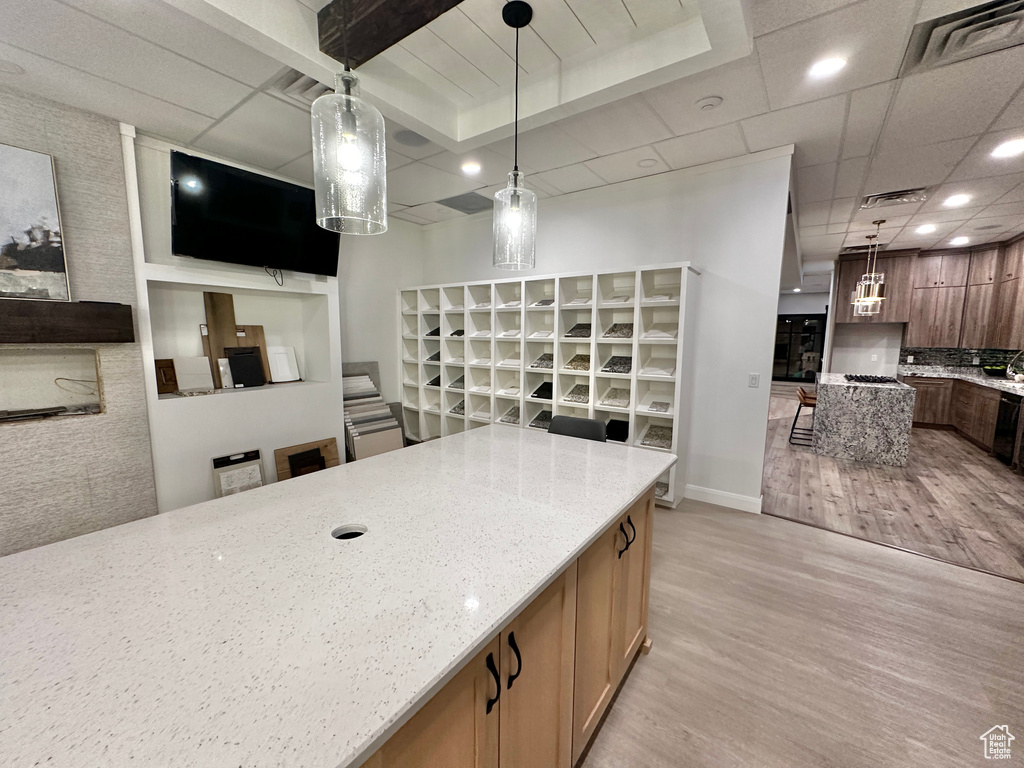 Kitchen featuring light stone countertops, decorative light fixtures, a kitchen breakfast bar, and light wood-type flooring