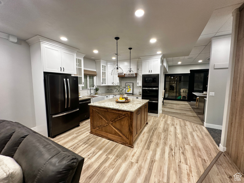 Kitchen featuring backsplash, white cabinetry, black appliances, and light hardwood / wood-style flooring