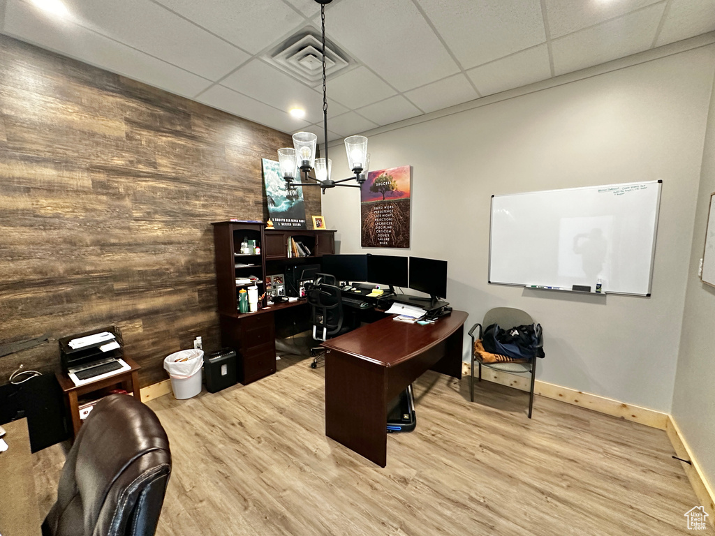 Home office featuring an inviting chandelier, hardwood / wood-style floors, and a drop ceiling