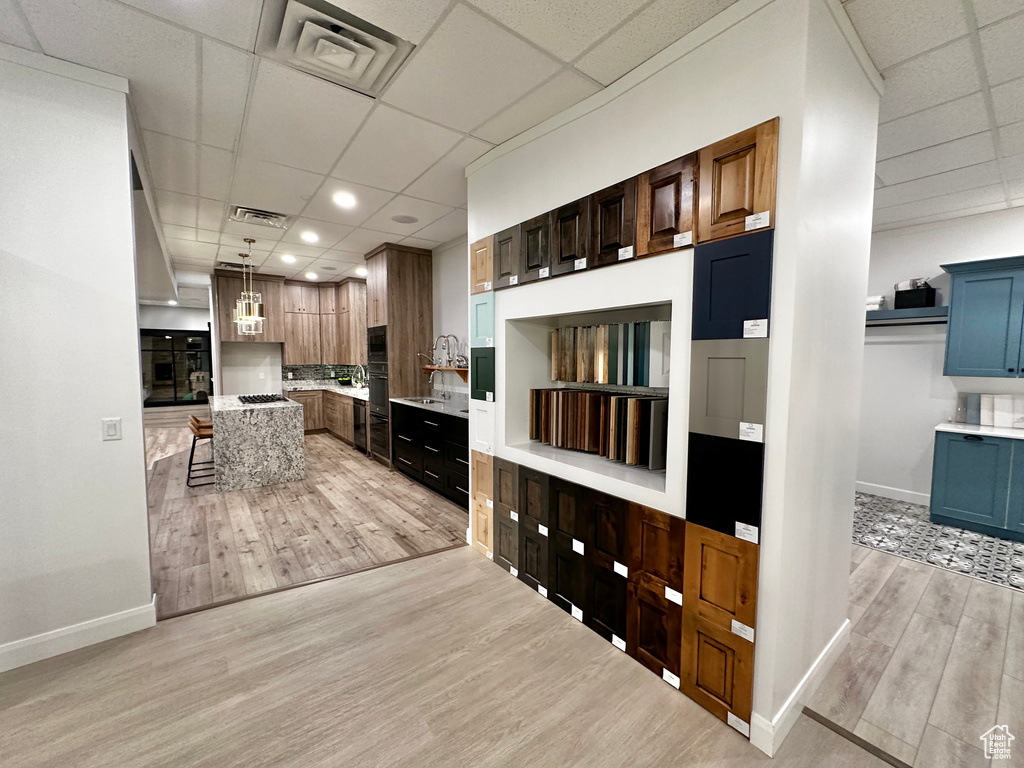 Kitchen featuring tasteful backsplash, a paneled ceiling, light hardwood / wood-style floors, and pendant lighting