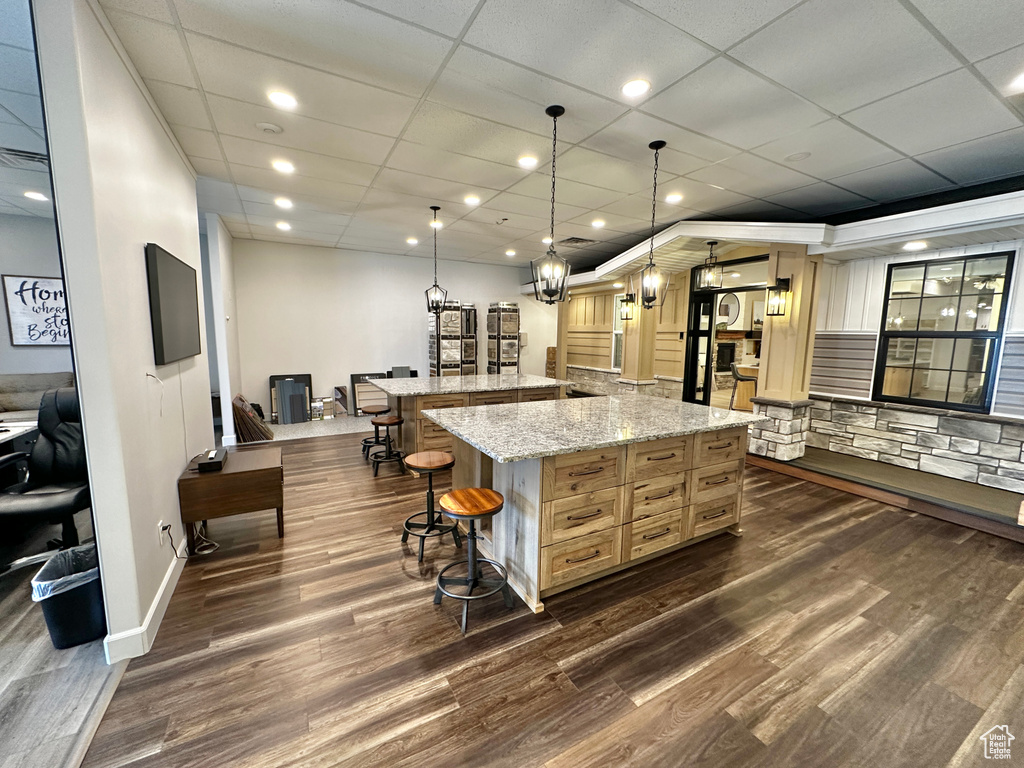 Kitchen with dark hardwood / wood-style floors, a kitchen bar, pendant lighting, and a drop ceiling