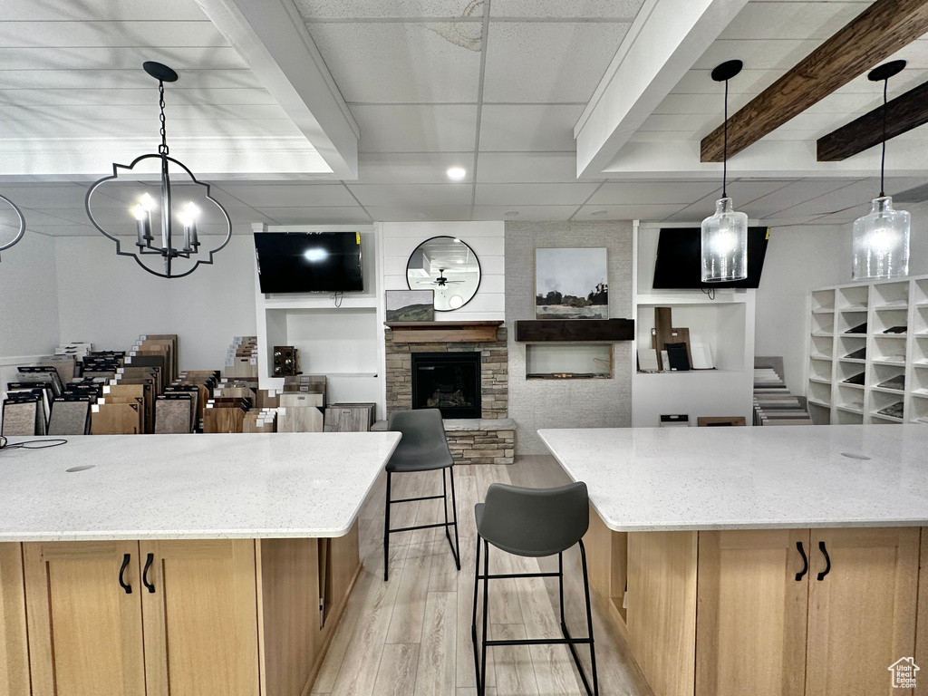 Kitchen featuring light stone countertops, a paneled ceiling, light hardwood / wood-style flooring, and pendant lighting