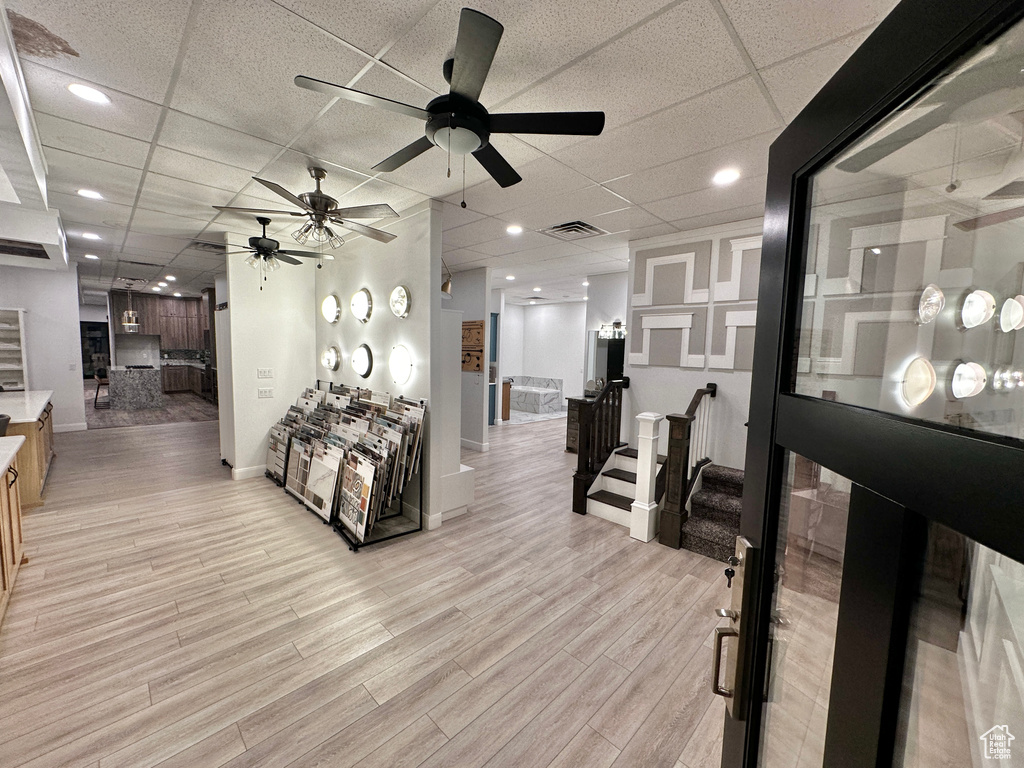 Living room with ceiling fan, light hardwood / wood-style flooring, and a drop ceiling